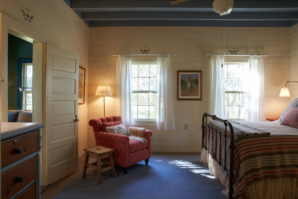 The main bedroom has rustic
finishes and decorative painting
above the doors. The exposed joist ceiling was painted blue. (Photography Pär Bengtsson)