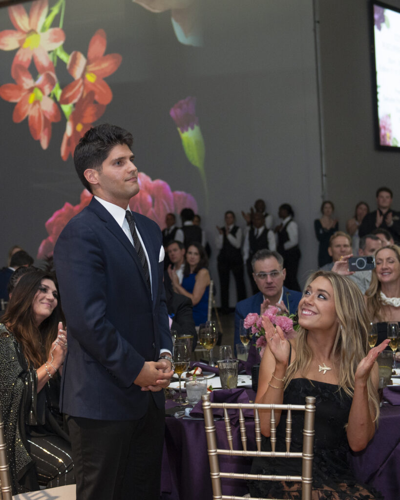 Artist Costa Christ during live auction, cheered on by wife Jackie (right) (Photo by Tamytha Cameron)