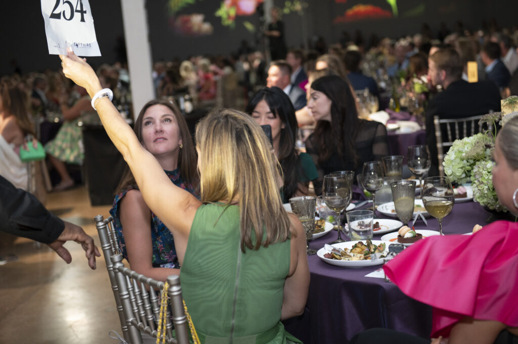 Gina Dunn raises her paddle (Photo by Tamytha Cameron)