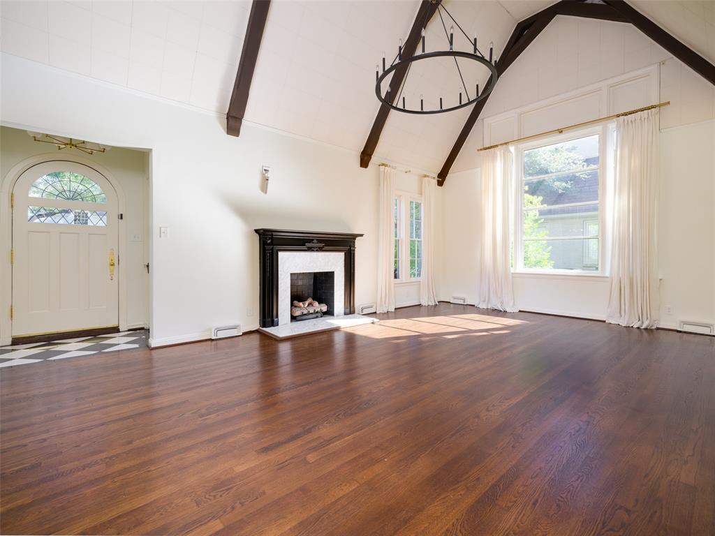 The living room features a cathedral ceiling with an open beam design and offers an attached sunroom that overlooks the backyard.