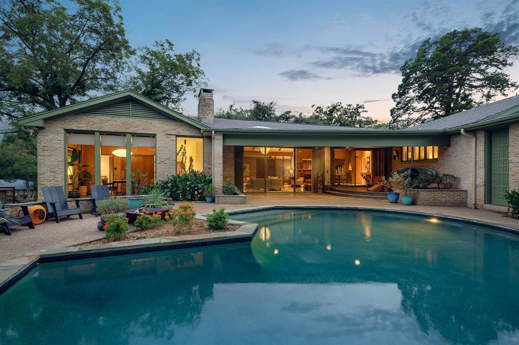 A spacious .44-acre lot boasts a pool and large windows, creating an indoor-outdoor atmosphere.