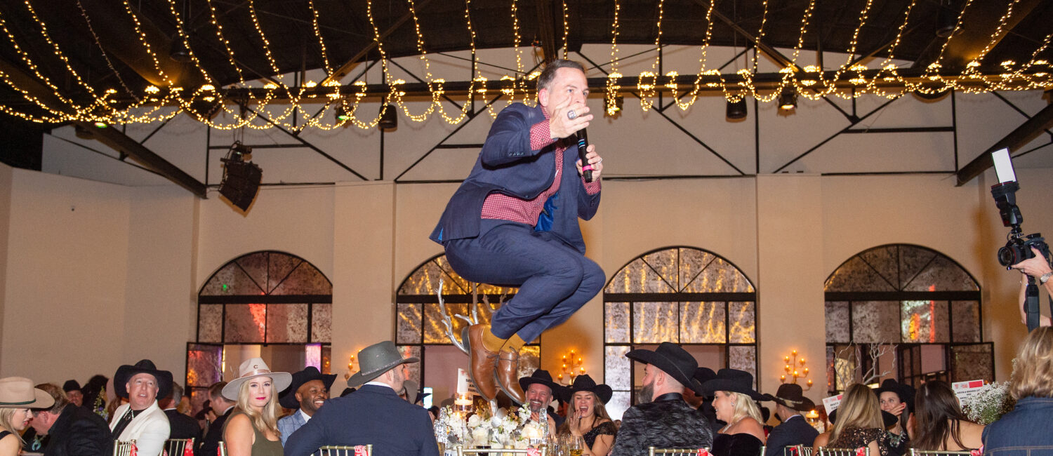 Auctioneer Johnny Bravo takes a leap at Crime Stoppers record breaking gala held at The Revaire. (Photo by Jacob Power)