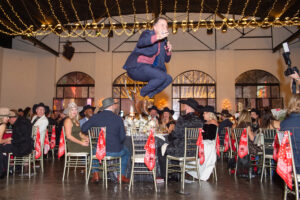 Auctioneer Johnny Bravo takes a leap at Crime Stoppers record breaking gala held at The Revaire. (Photo by Jacob Power)