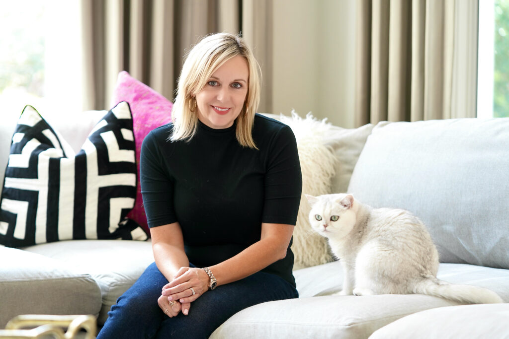 Owner and principal designer Laura Starzyk and the owner's cat share a moment on the new couch.