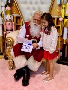 Patient ambassador Olivia with NorthPark Santa, reviewing her list (Photo by Kim Leeson)