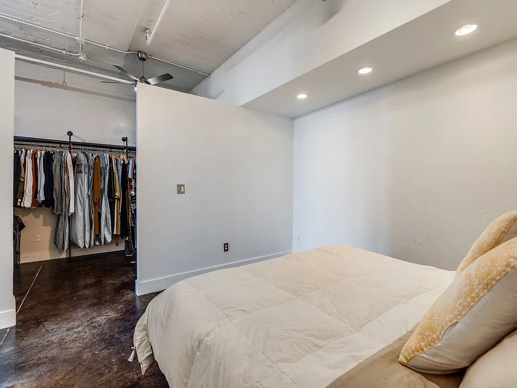 The condo features original concrete floors, exposed brick, visible ductwork, high ceilings, and metal windows.