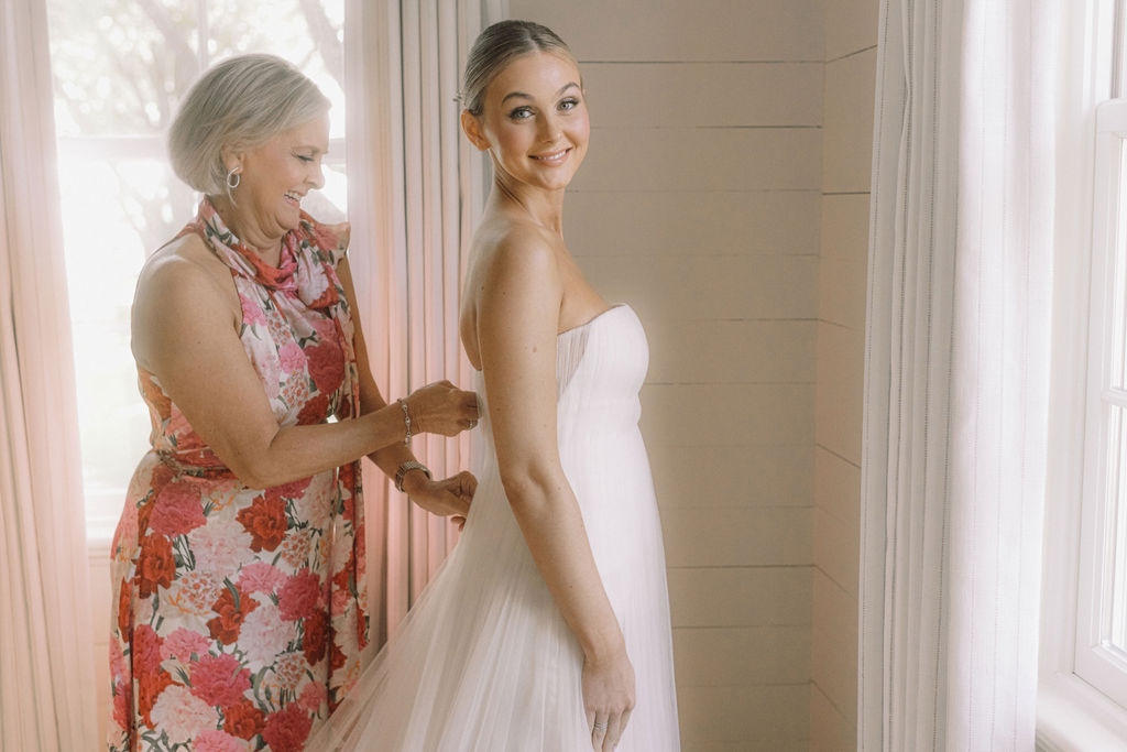 The bride's mother, Brenda Wempe, assists her daughter with her Vera Wang wedding gown. (Photo by Joseph West Photography)