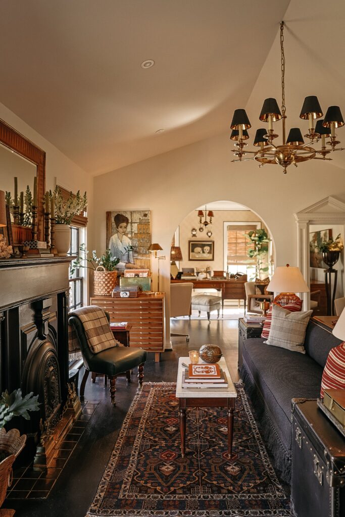 Upon entry, the bright and spacious living room boasts a vaulted ceiling, decorative fireplace, and a dramatic brass chandelier. (Photo by Beckley)