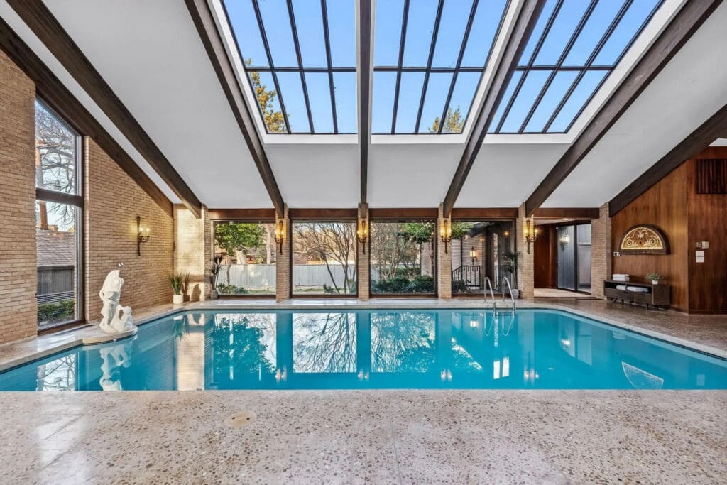The indoor pool area, which also includes a wet bar and library, showcases this harmonious connection between indoor and outdoor living. (Photo by Compass RE Texas)