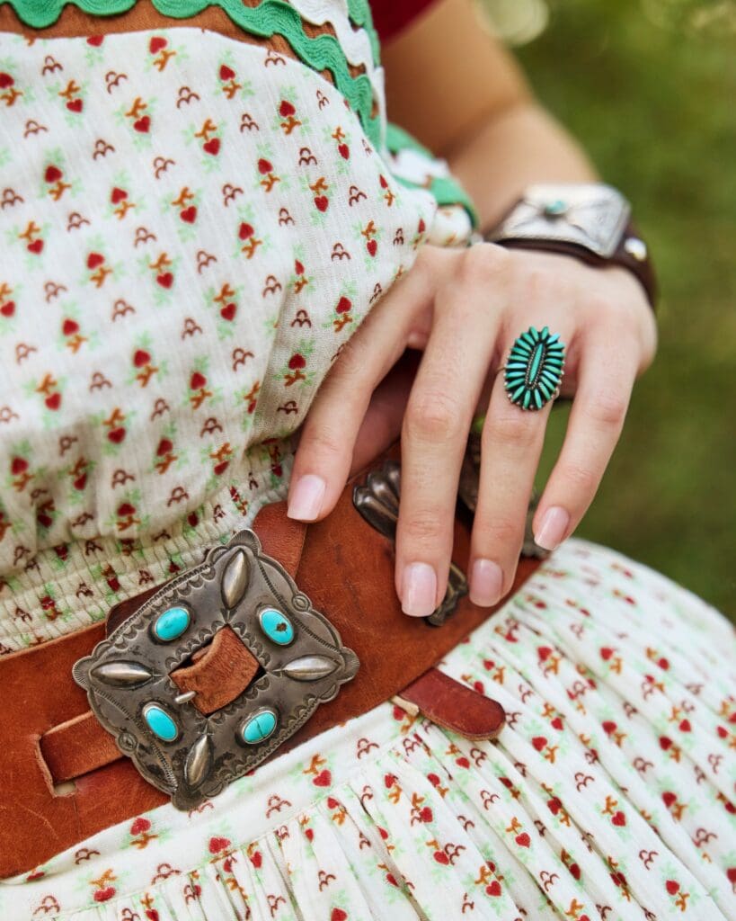 The vintage Double D Ranch belt features a wide, worn leather strap with a large silver buckle decorated with turquoise stones and engraved detailing. (Courtesy)
