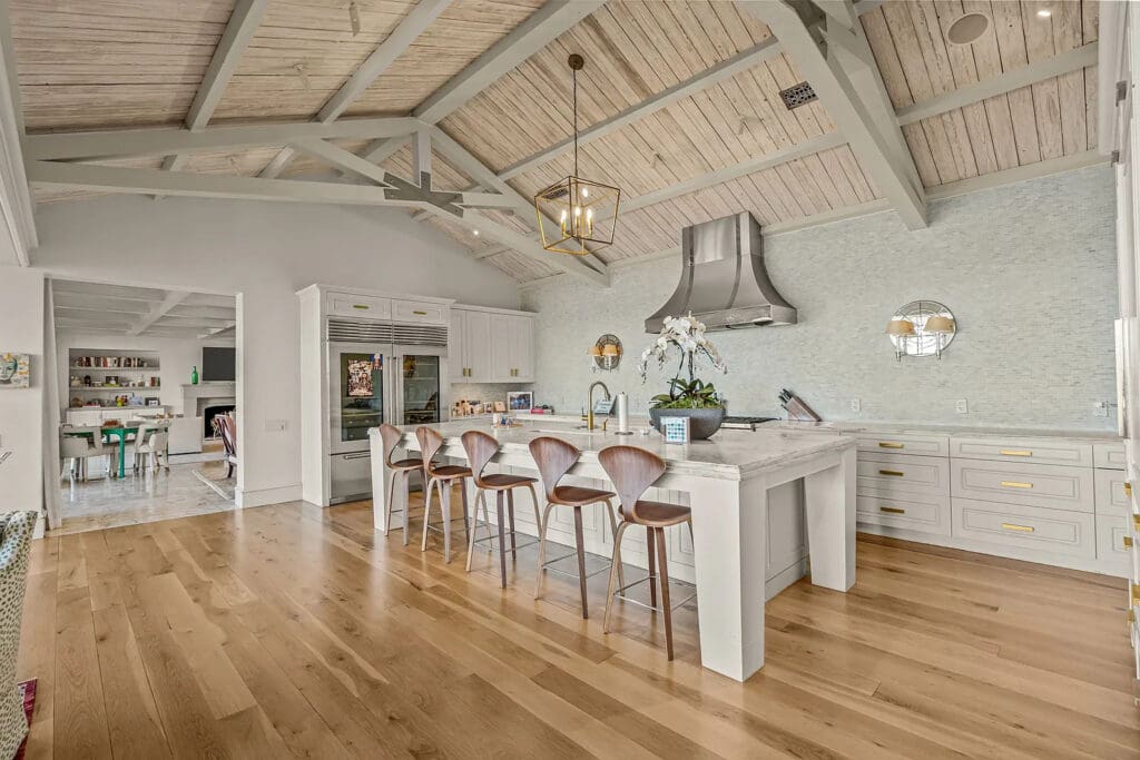 Vaulted ceilings and exposed beams frame a chef’s kitchen with an oversized island and luxury finishes. (Courtesy)