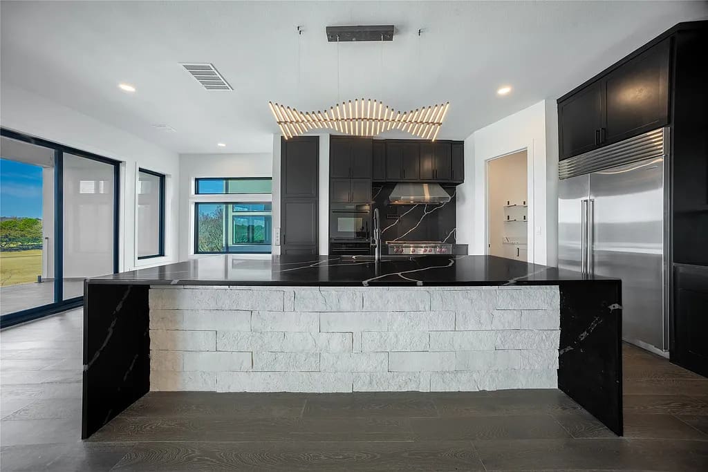 Glossy black quartz, stacked stone, and custom lighting give the kitchen at 4732 Villa Terrace a bold, sculptural edge. (Courtesy)