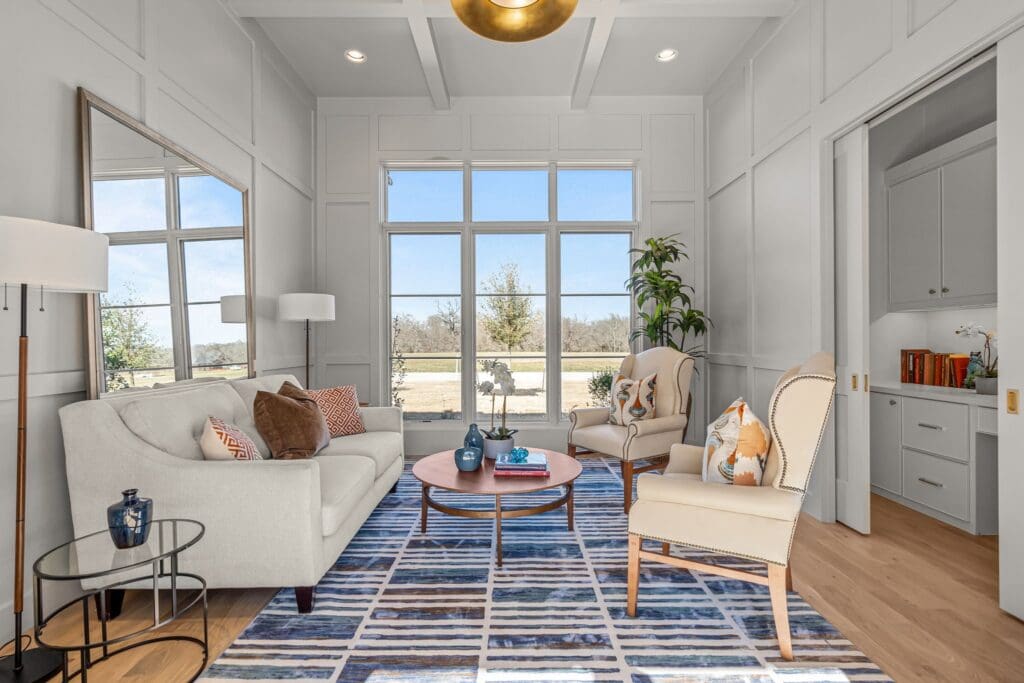 Tall windows, coffered walls, and pocket doors define this sun-drenched sitting room at 9825 Loire Valley Trail. (Courtesy)