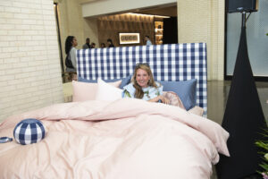 Caroline Harrison trying out the Hästens King Maranga bed, which was up for bidding on the event's Big Board (Photo by Tamytha Cameron Photography)