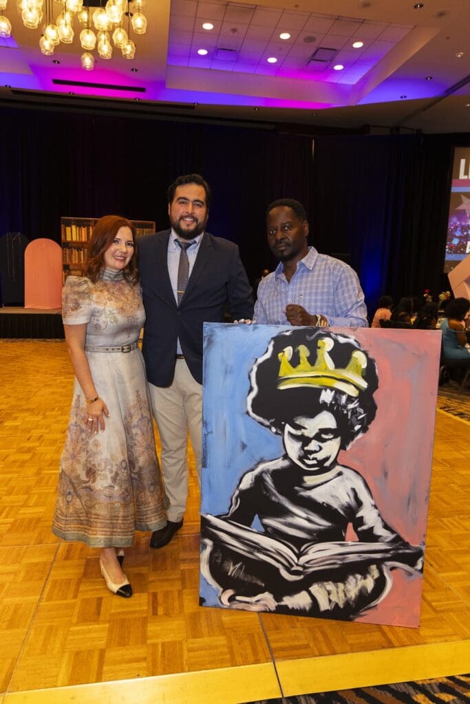 Ange Hillz stands with guests beside one of his paintings during Jack and Jill’s 2025 Pink and Blue gala at The Woodlands Resort. (Photo by 209 Photo Booth)