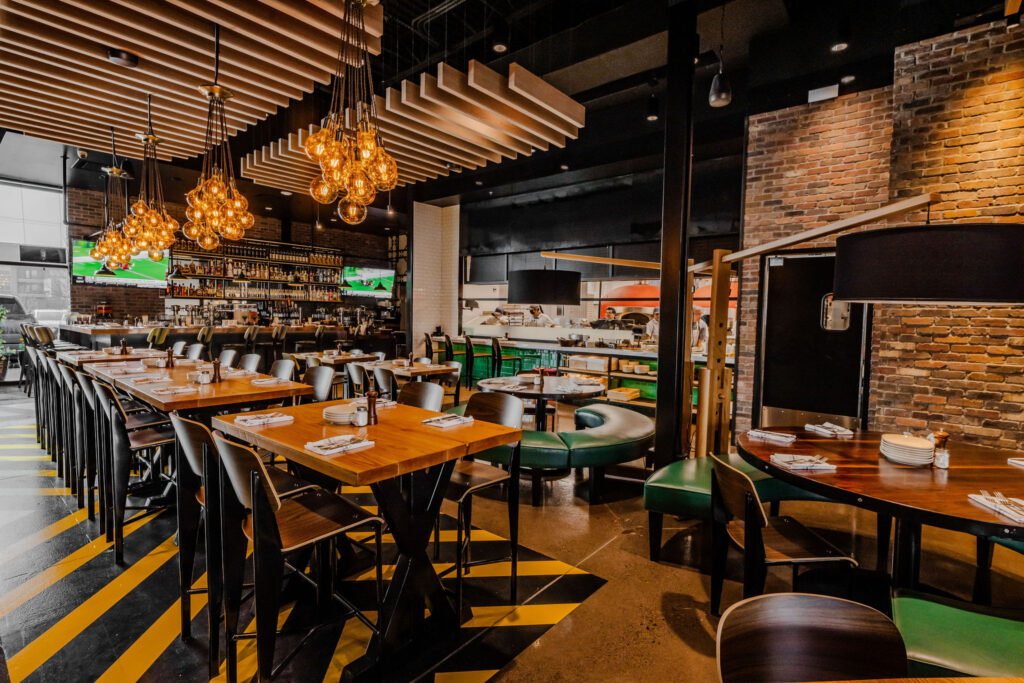 Pie Tap's light-filled space features a workshop-inspired aesthetic, complete with an exhibition kitchen, industrial lighting, and mosaic-tiled walls, providing guests with a front-row seat to the pizzaiolo's action.