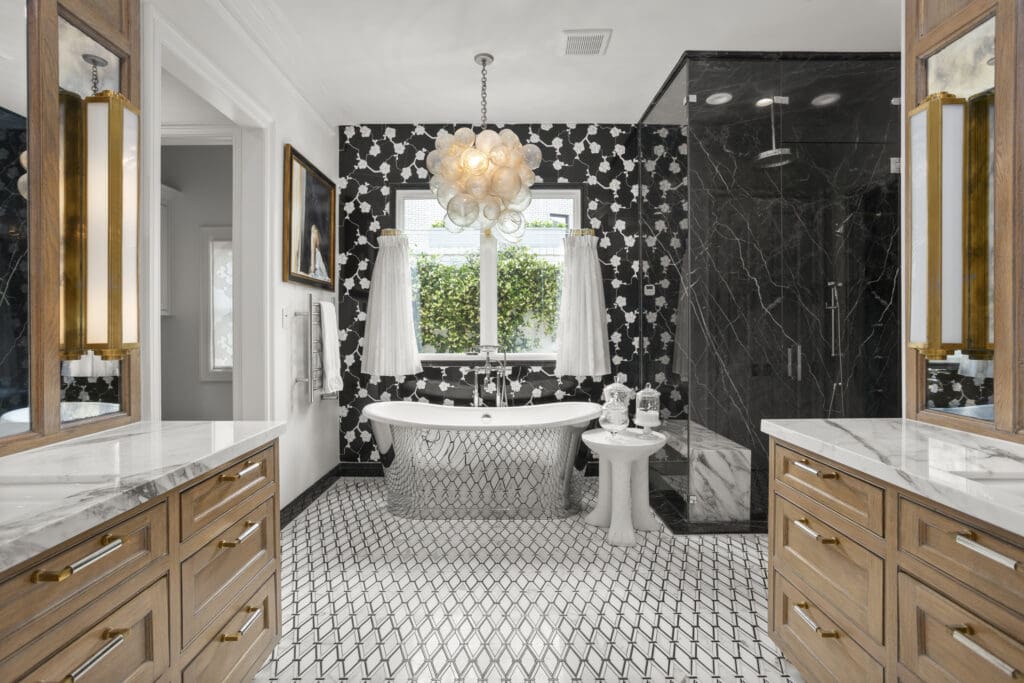 Bold black marble, graphic tilework, and a sculptural chandelier define the primary bath, which pairs vintage glamour with precision craftsmanship. (Freeze Media)