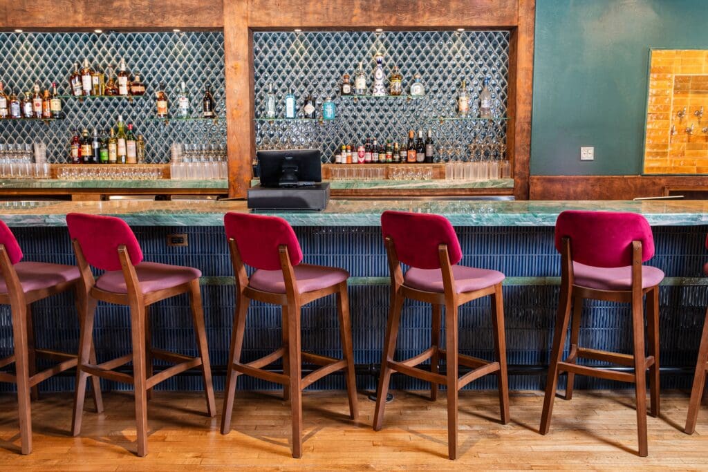 The bar area inside Good God, Nadine's features a bar wrapped in tile lit with brass accented lighting. (Photo by Becca Wright)