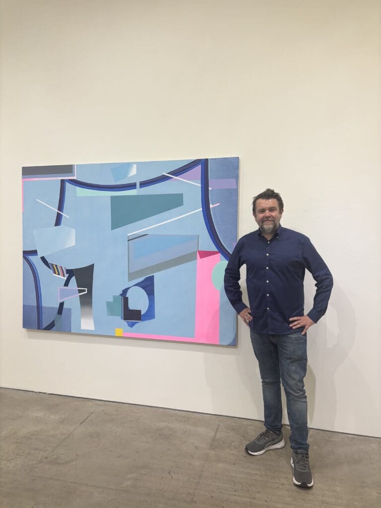 Artist Danny Rolph stands next to his acrylic on canvas painting "Sonnet 116," 2025, in the Barbara Davis Gallery. His exhibit, "Trippin' Over the Ocean" remains on view through July 5. (Photo by Ericka Schiche)