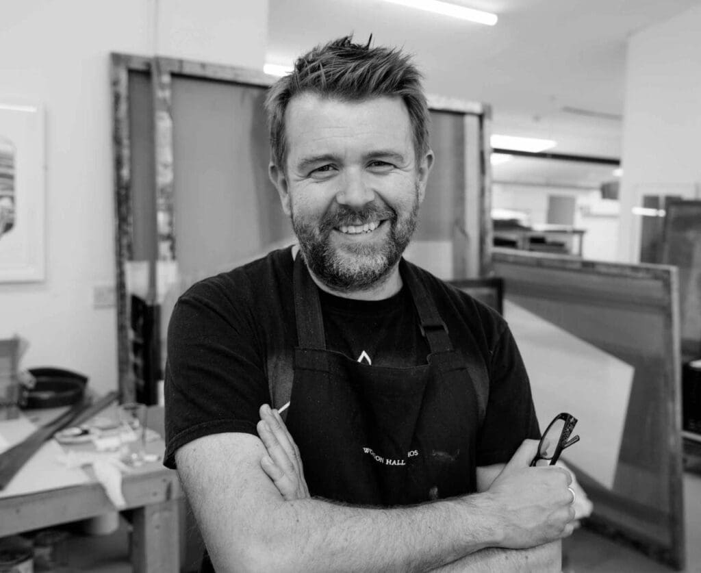 Artist Danny Rolph smiles while taking a break from working on his art in a print shop. (Courtesy CCA Galleries)