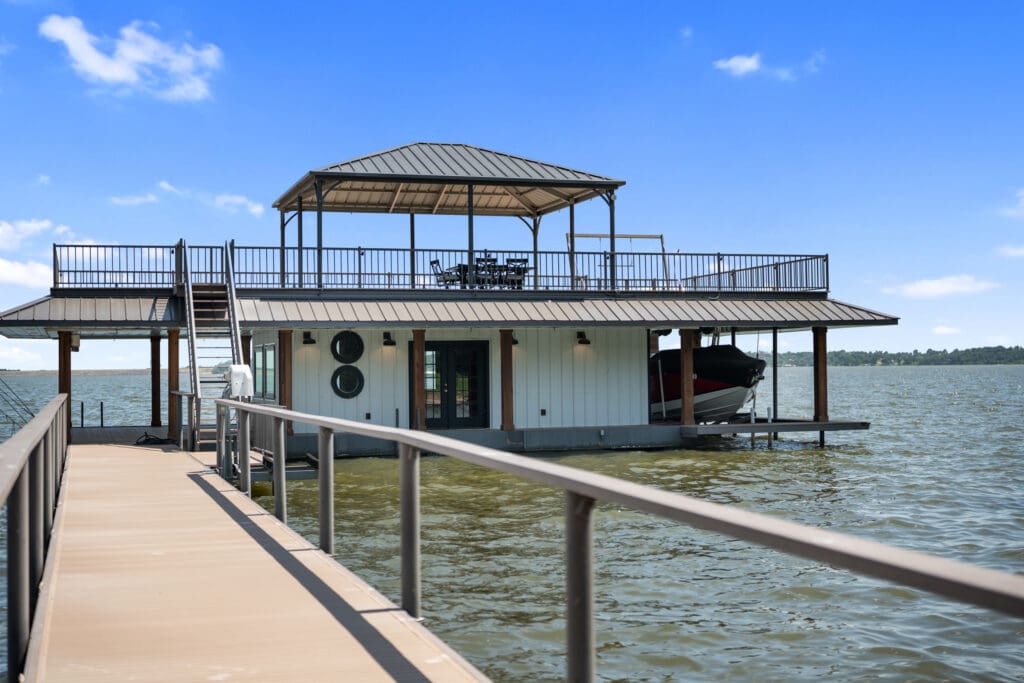 A two-story dock includes a covered lounge area, boat slips, and a climate-controlled game room over the water. (Photo by The Ashton Agency)