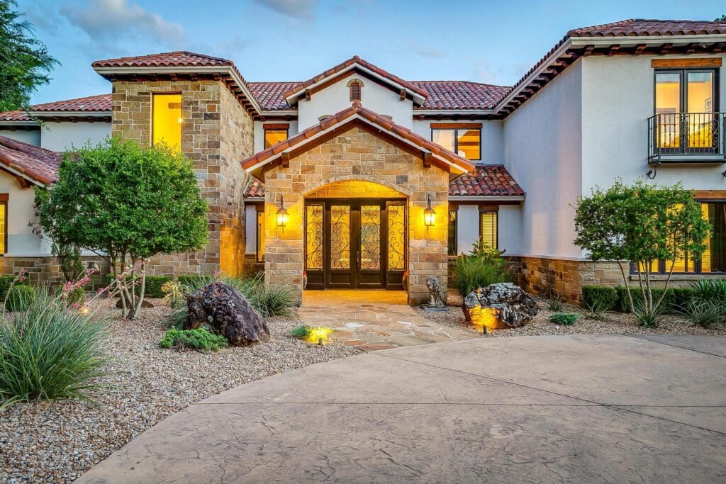Mediterranean character shines through the main home’s stone façade, clay tile roof, and wrought iron entry. (Photo by The Ashton Agency)