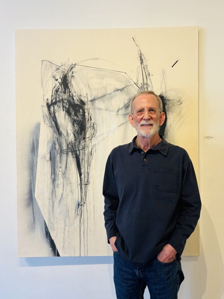 Harold Joiner, director of the artist-owned Archway Gallery, stands near Lawrence Lange's acrylic, ink and charcoal on canvas work "A Once Proud and Noble Man" in Archway Gallery. The gallery's 17th Annual Juried Exhibition remains on view through July 31, 2025. (Photo by Ericka Schiche)