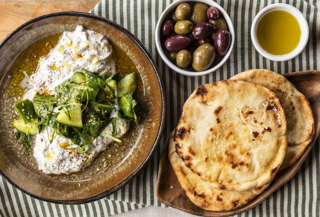 Best served family-style, start by sharing mezédes like tzatziki (pictured) the garlic-scented, smashed cucumber Greek yogurt dip ($13) at the new Yiayia restaurant. (Photo by Julie Soefer)