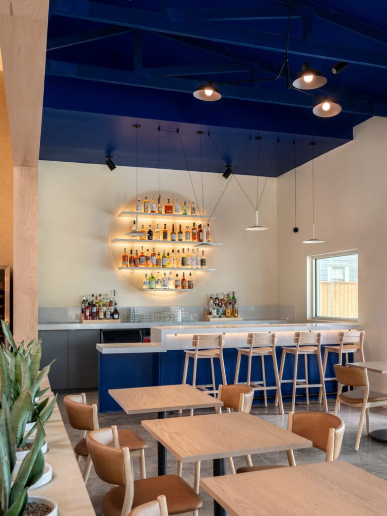 The clean-lined interior of Camaraderie has warm, light woods and a vaulted ceiling with skylights that bathe the room in natural light. Three sections — dining room, bar, and lounge — focus on a market-driven menu of contemporary American cuisine rooted in French technique. Photo by Leonid Furmansky.