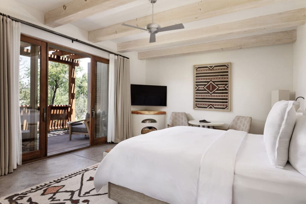Beyond the stucco exterior, tranquil guest rooms feature wood beams, a kiva fireplace, a courtyard with an outdoor fireplace, and a dreamy Southwestern color palette. (Photo by Four Seasons Resort Rancho Encantado Santa Fe)