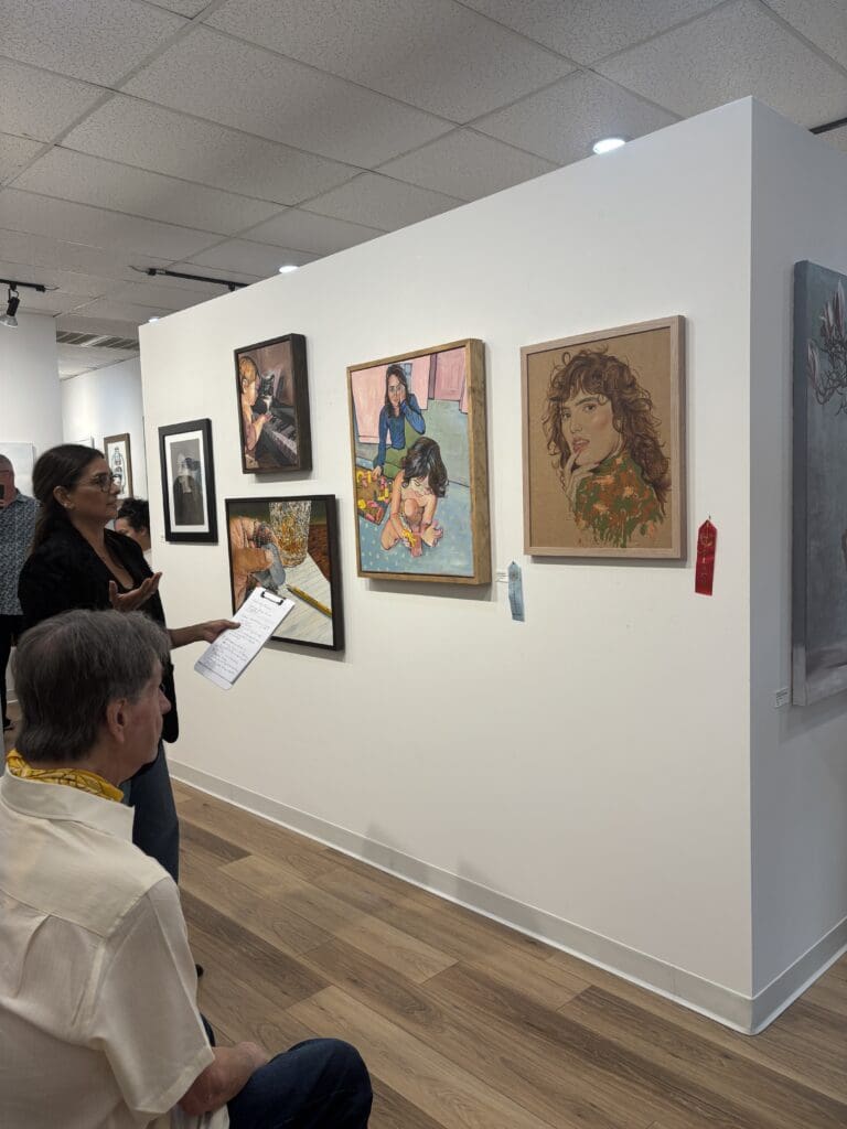 Guest juror Gabriella Monterroso with the Honorable Mention and Second Place works at Ardest Gallery’s "Modern Mirrors" exhibit. (Photo by Laura Landsbaum)