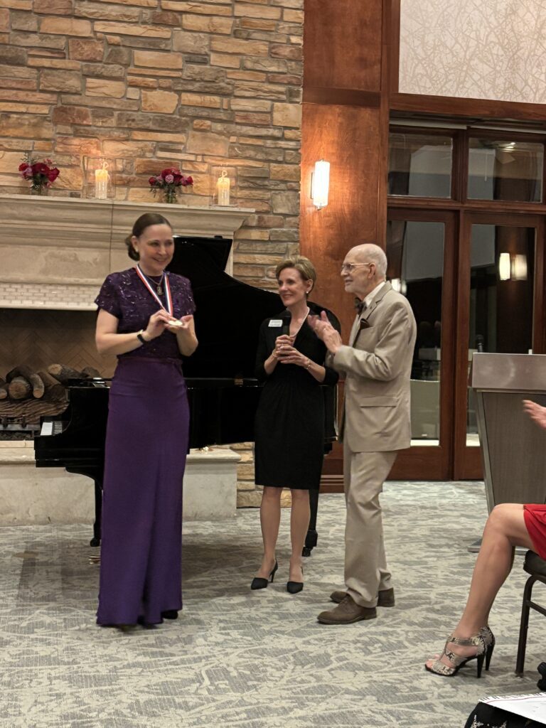 Malan received her medal, from Jim Pokorski with Susan Moore Pokorski.  Susan explained that in 1998, YTA's budget did not allow them to award medals. (Photo by Laura Landsbaum)