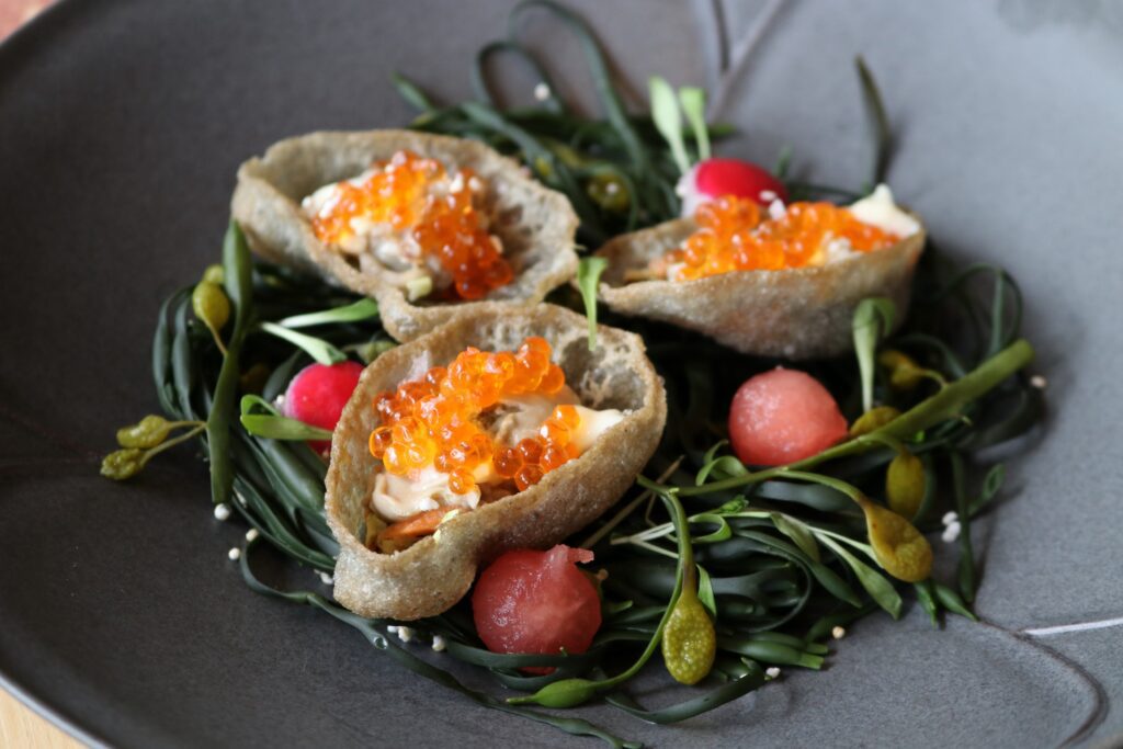 Discover a dish of the Ortegas' own making at Zaranda where a deep-fried Gulf oyster, devoid of its outer shell, is swaddled in a custom-molded edible shell with a bed of coleslaw, smoked oyster aioli, and glowing orange trout roe. (Photo by Paula Murphy)