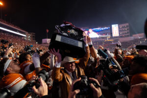 Cotton Holdings Founder and Chairman Pete Bell carrying the Lone Star Showdown Trophy to the winning Texas Longhorns; photo courtesy of Texas Athletics