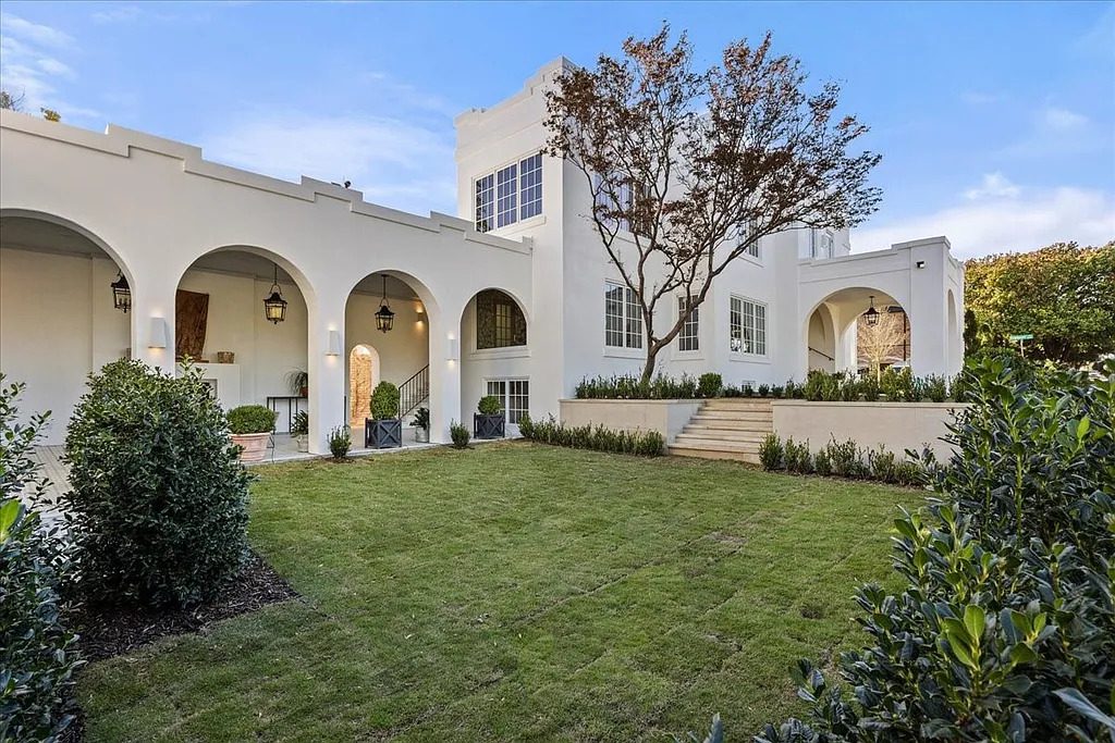 The rear elevation opens to a manicured lawn and arched outdoor living spaces, reinforcing the home’s indoor-outdoor flow. (Courtesy)