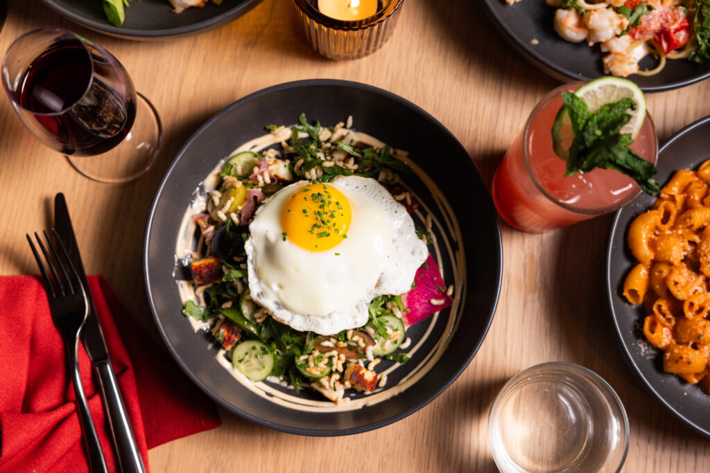 The Crispy Rice Bowl at Little Ruby's features puffed wild rice, halloumi, a sunny-side egg, fresh vegetables, and ginger lemon dressing. (Photo by Ashley Randall Photography)