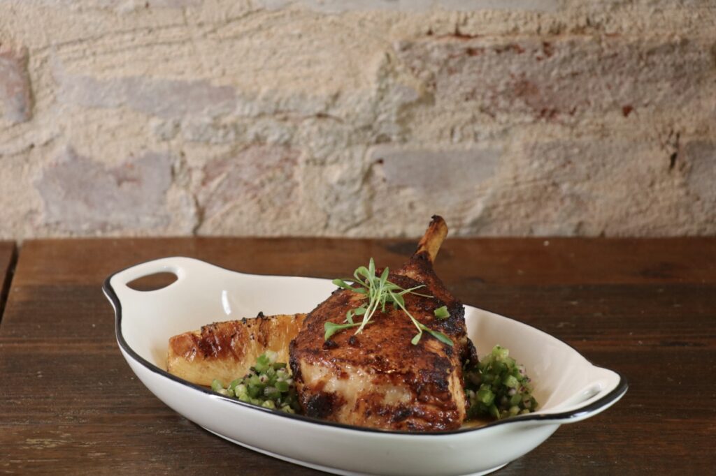 On a recent visit, a bone-in Berkshire pork chop that came with a large piece of roasted pineapple, green pico, and tortillas.  (Photo by Burciaga Hospitality Group)