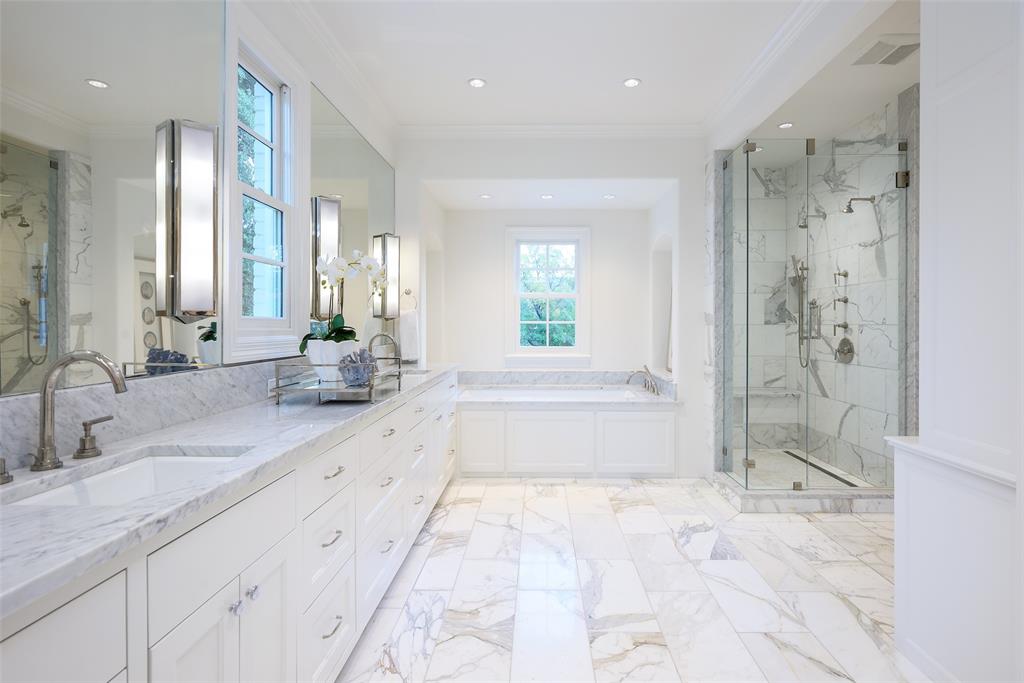 The striking marble bath offers dual vanities (duh), a deep soaking tub, separate shower, and a large-and-in-charge custom closet. (Photo by Compass RE Texas, LLC)
