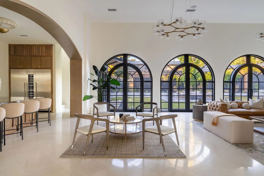 In the open-concept living space with soaring ceilings, sun streams through the wall of arched windows. (Photo by Compass RE Texas, LLC)