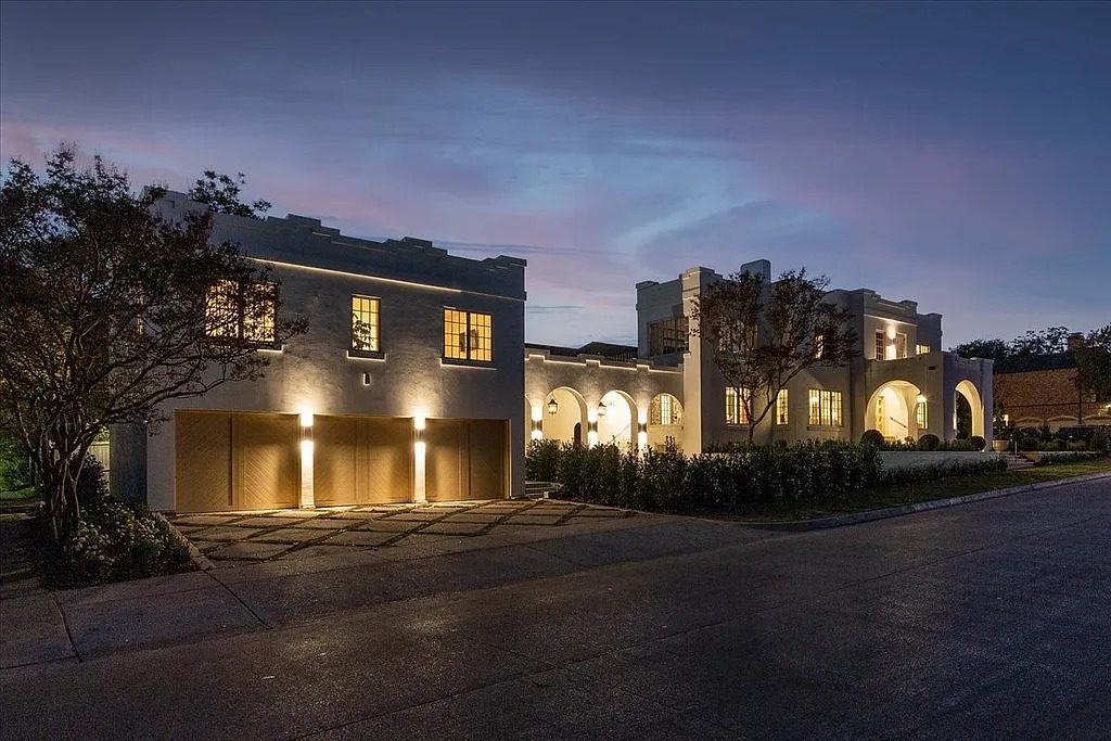 Exterior lighting highlights the home’s arched loggias and crisp white stucco façade. (Courtesy)