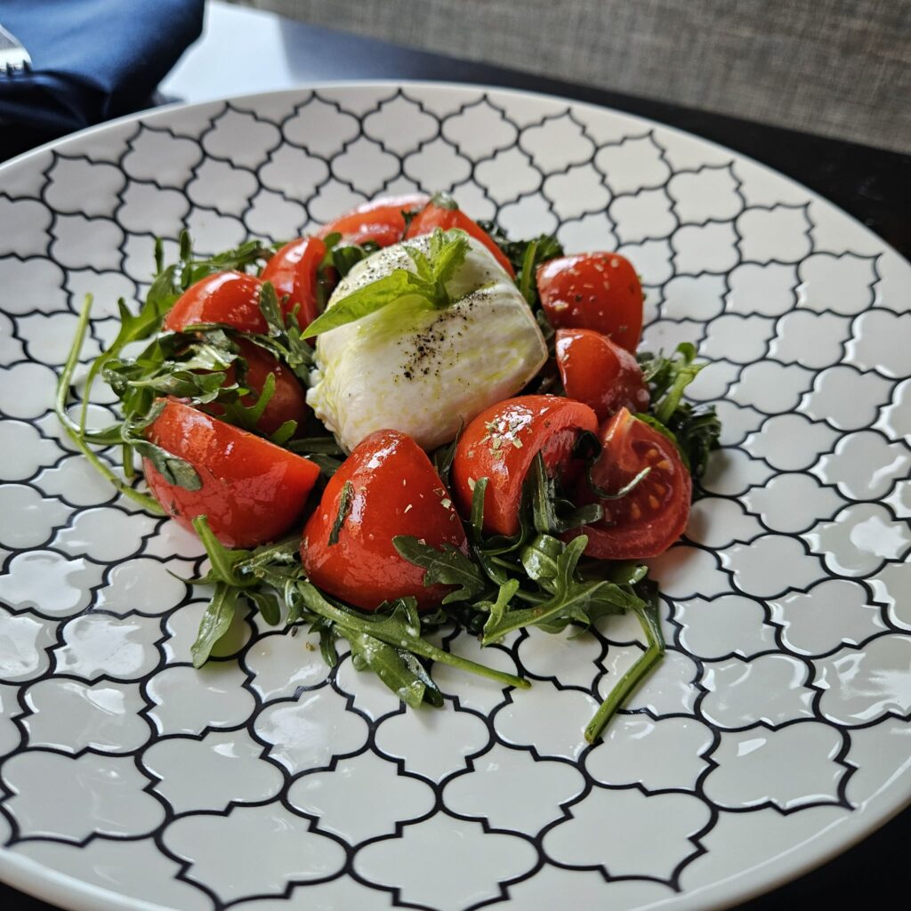 The burrata con pomodorini at Felina is a simple but vibrant trio of fresh cherry tomatoes, creamy burrata, and peppery arugula, finished with olive oil and basil. (Courtesy)