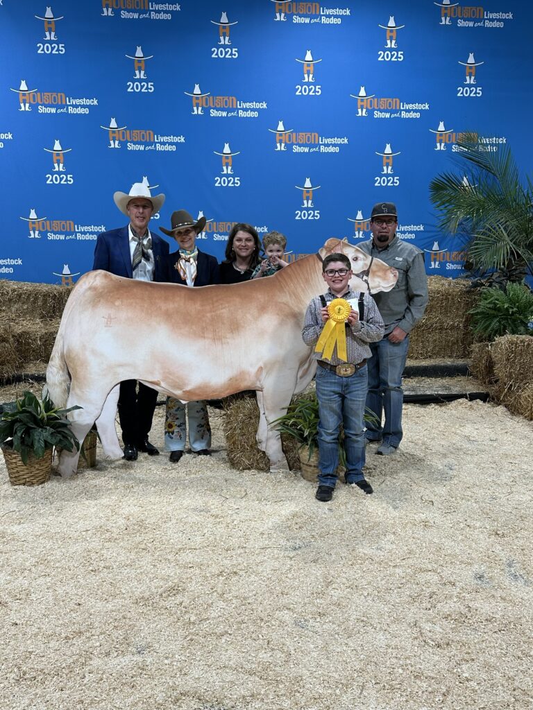 A proud youngster shows off his ribbon from the 2025 Junior Market Steer Auction. 