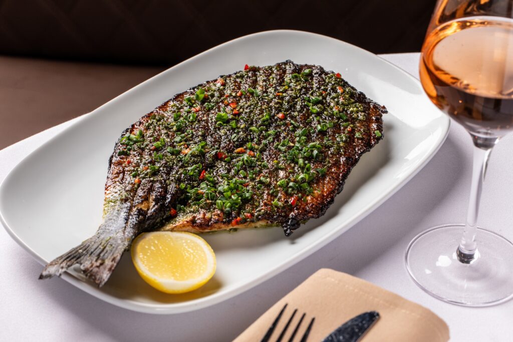 The grilled branzino entree ($48) is napped with chimichurri and a citrus mojo. Photo by Madelynne Grace.