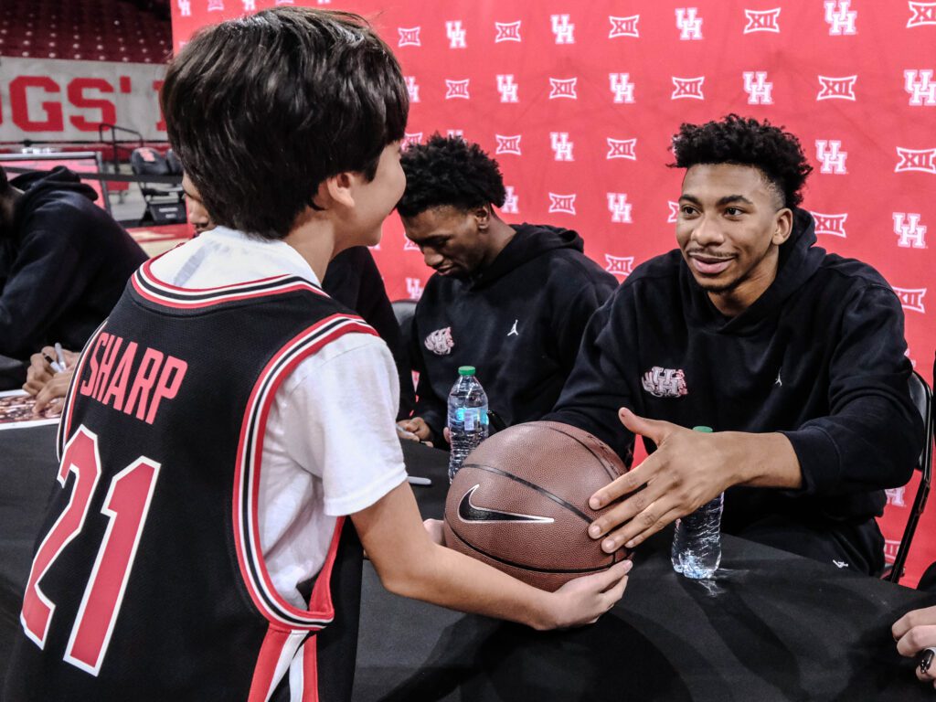 University of Houston forward Chase McCarty signs a basketball for a fan in an Emanuel Sharp jersey. (Photo by F. Carter Smith)