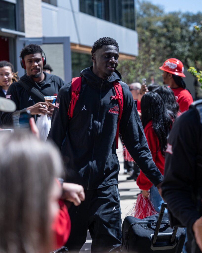 Cedric Lath wears the new Beats headphones UH guard Milos Uzan gave him as he walks to the bus with fellow center Kalifa Sakho. (@UHCougarMBK)