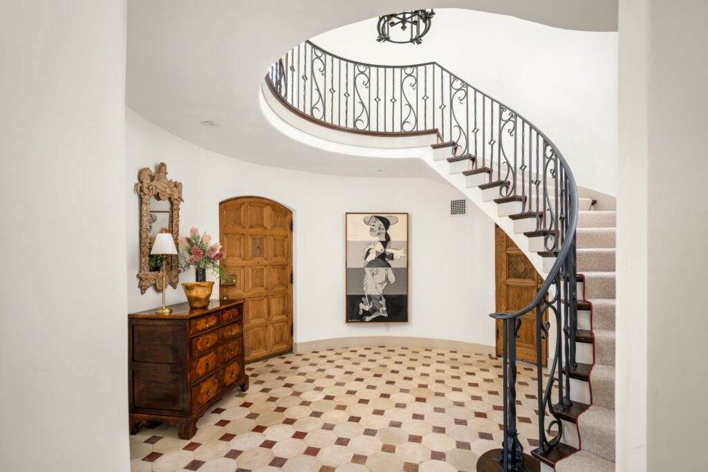 Chateau-Domingue antique patterned tile and a sculptural curved stair at the entry set the tone for 1419 Kirby (Photo by Sonya Bertolino / Compass)