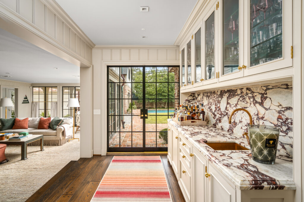 Custom millwork and glass-front cabinetry in the bar area, situated off the butler’s pantry and adjacent to the family room (Photo by Sonya Bertolino / Compass)
