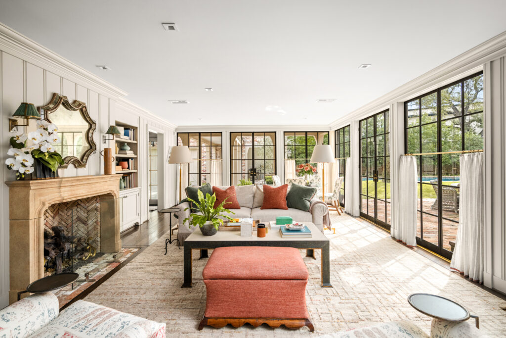 Inviting family room anchored by a traditional fireplace, framed by classic paneling and a wall of garden-facing windows (Photo by Sonya Bertolino / Compass)