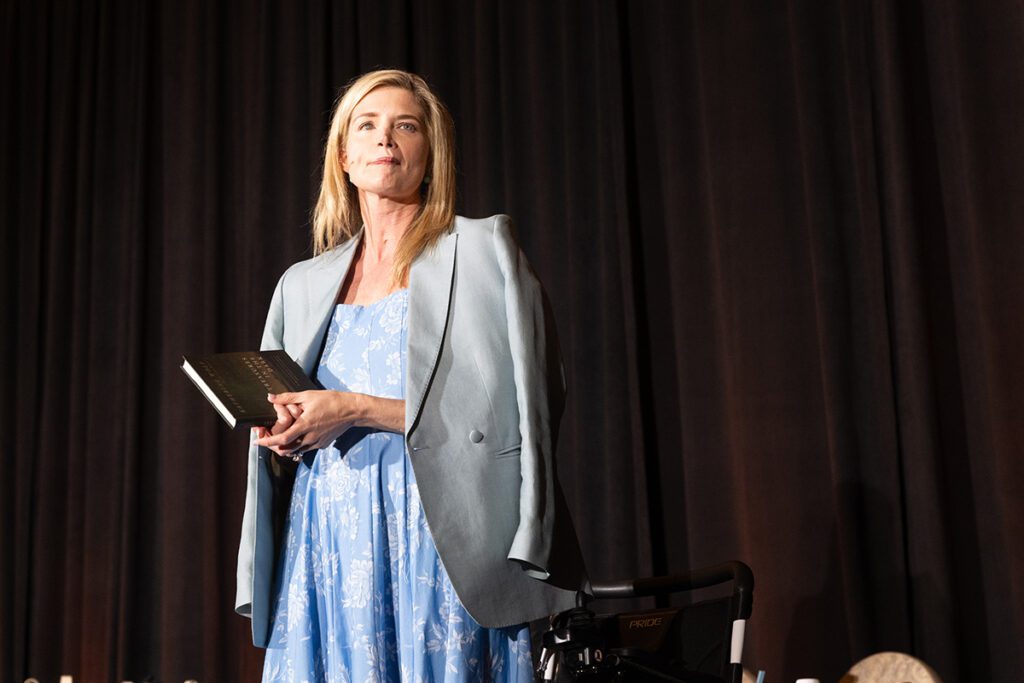 Keynote speaker, Katherine Wolf, standing from her wheelchair during her powerful message. (Photo credit: Daniel Ortiz)