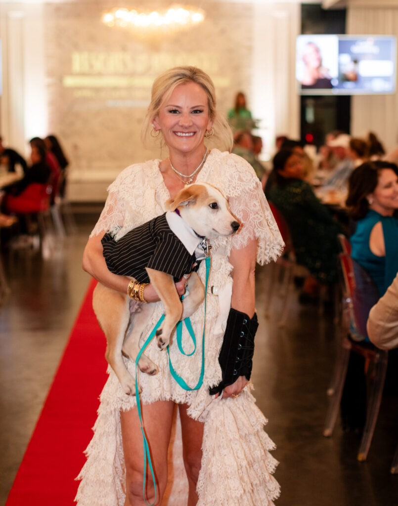 Carrie Greenberg cuddles a rescue on the runway during Operation Pets Alive’s Rescues on the Runway event at The Peach Orchard. (Photo by CS Wedding Co.)